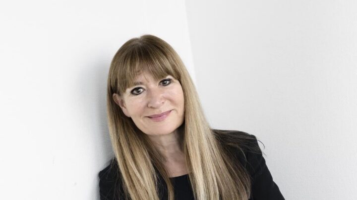 Bente Klarlund, professor - står foran hvid væg med hænderne over kors.