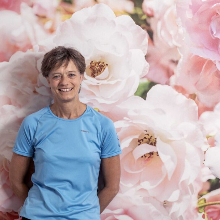 Gitte Møller Jensen står foran en væg med storblomstret motiv.