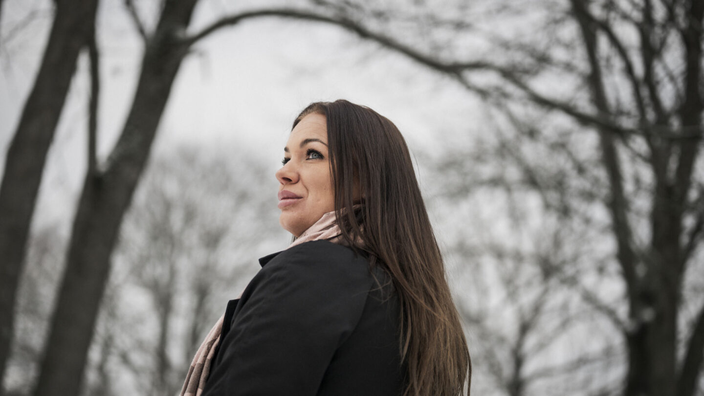 Patricia, der lever med gigt, står udendørs i park.