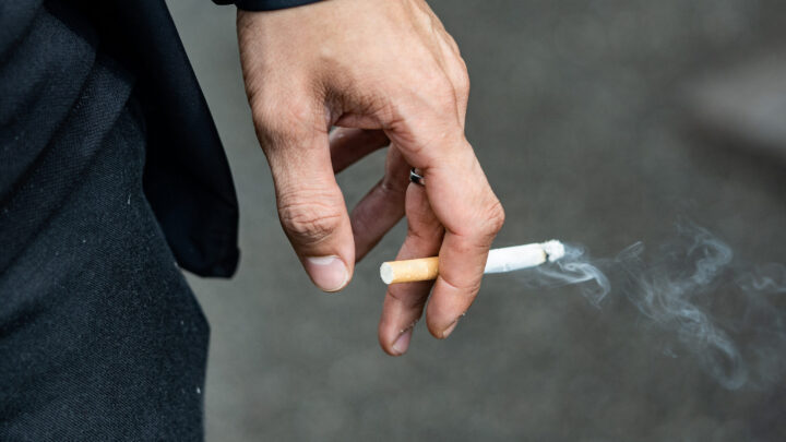 En rygende cigaret i hånden