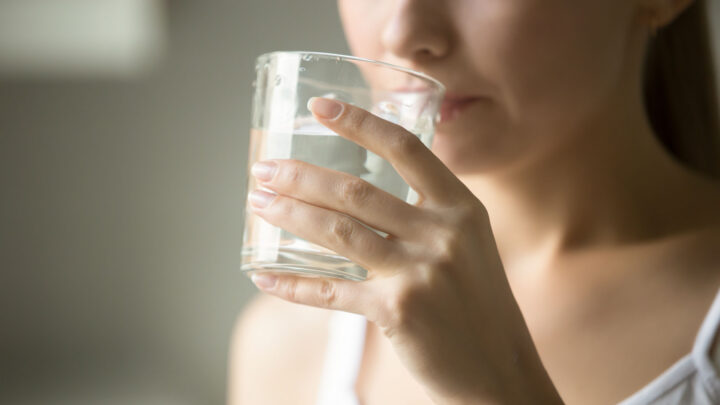 En person drikker et glas vand.