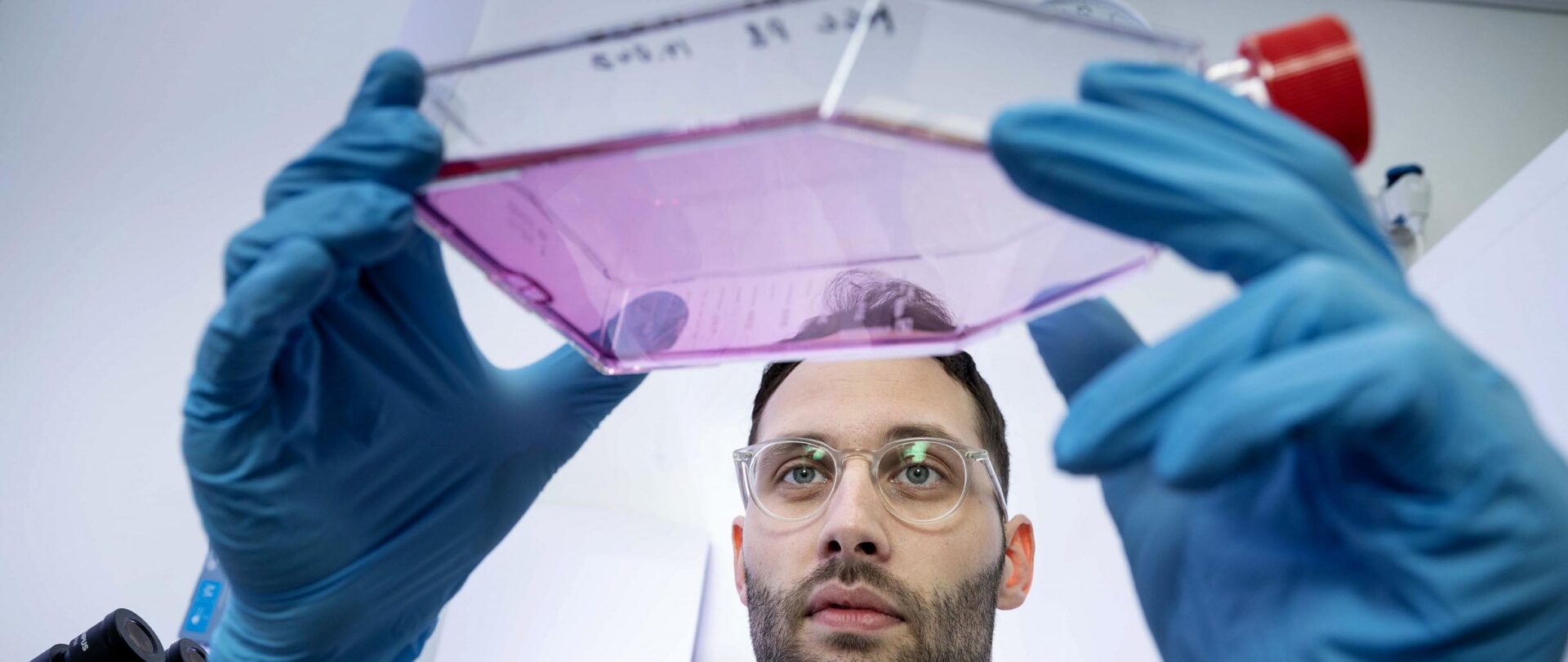 Gigtforsker Rasmus Roost Aabling i laboratoriet. hvor han holder beholder op med væske.