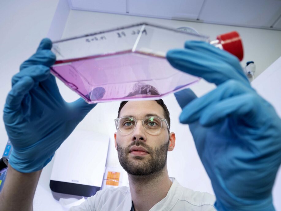 Gigtforsker Rasmus Roost Aabling i laboratoriet. hvor han holder beholder op med væske.