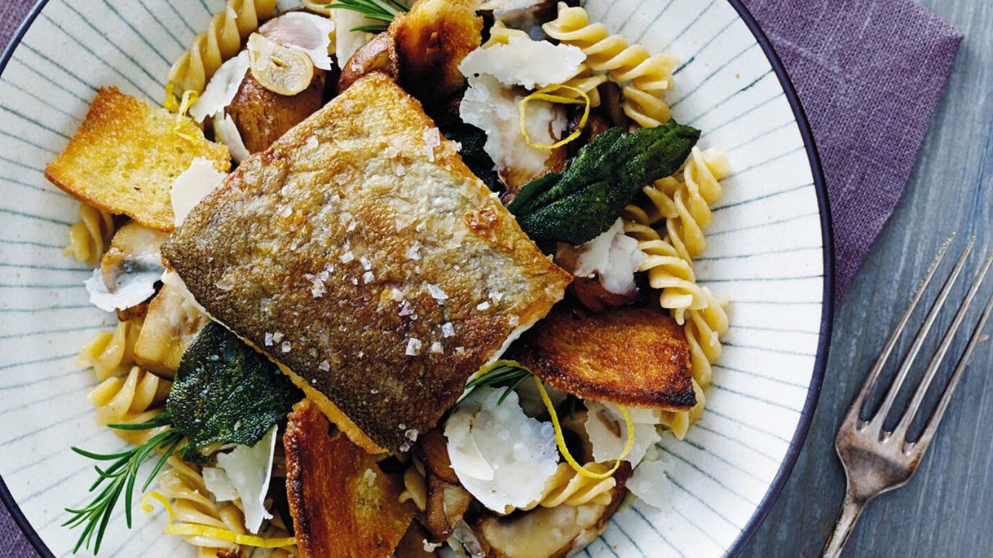 Marineret grillet ørred med pasta, grillede croutoner, salvie og svampe serveret på tallerken med striber
