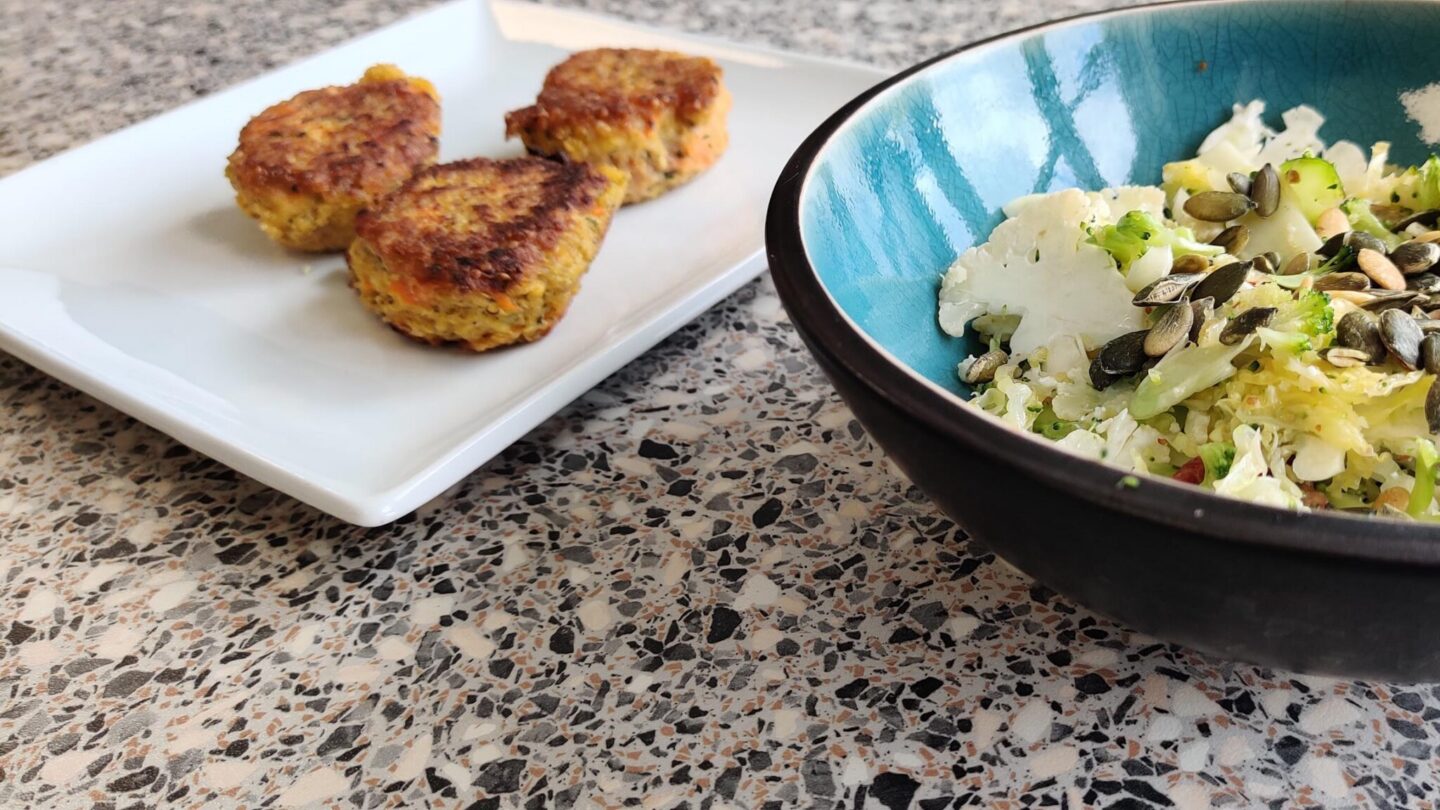 Quinoafrikadeller med gulerod serveret med kålsalat i turkis skål.