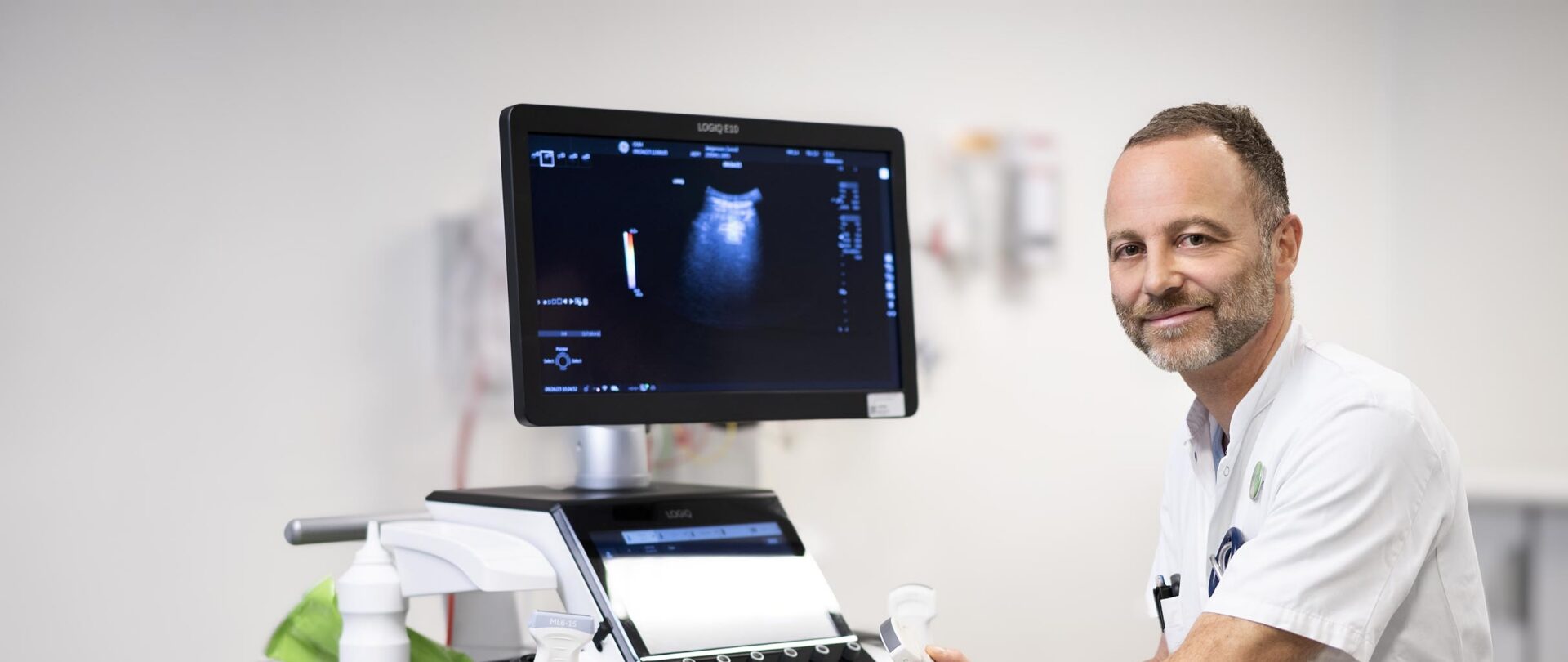 Gigtforsker sidder ved ultralydsscanner og skærm på hospital.
