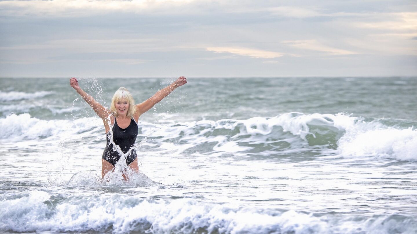En person bader i havet - rækker begge arme i vejret.