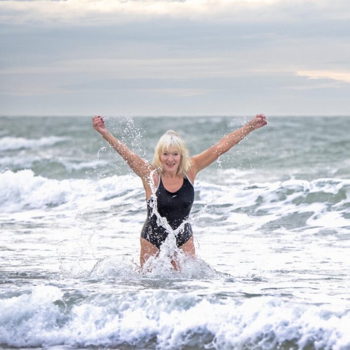 En person bader i havet - rækker begge arme i vejret.