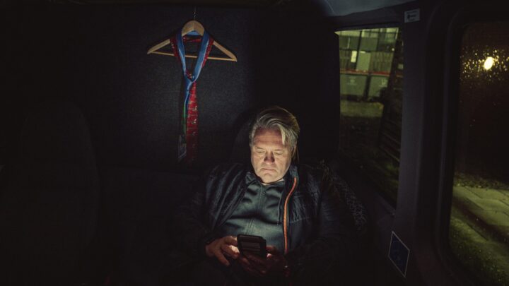Johnny Hansen fra bandet Kandis sidder i en bus og kigger på sin telefon i mørket.