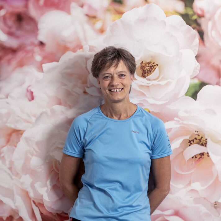 Gitte Møller Jensen står foran en væg med storblomstret motiv.